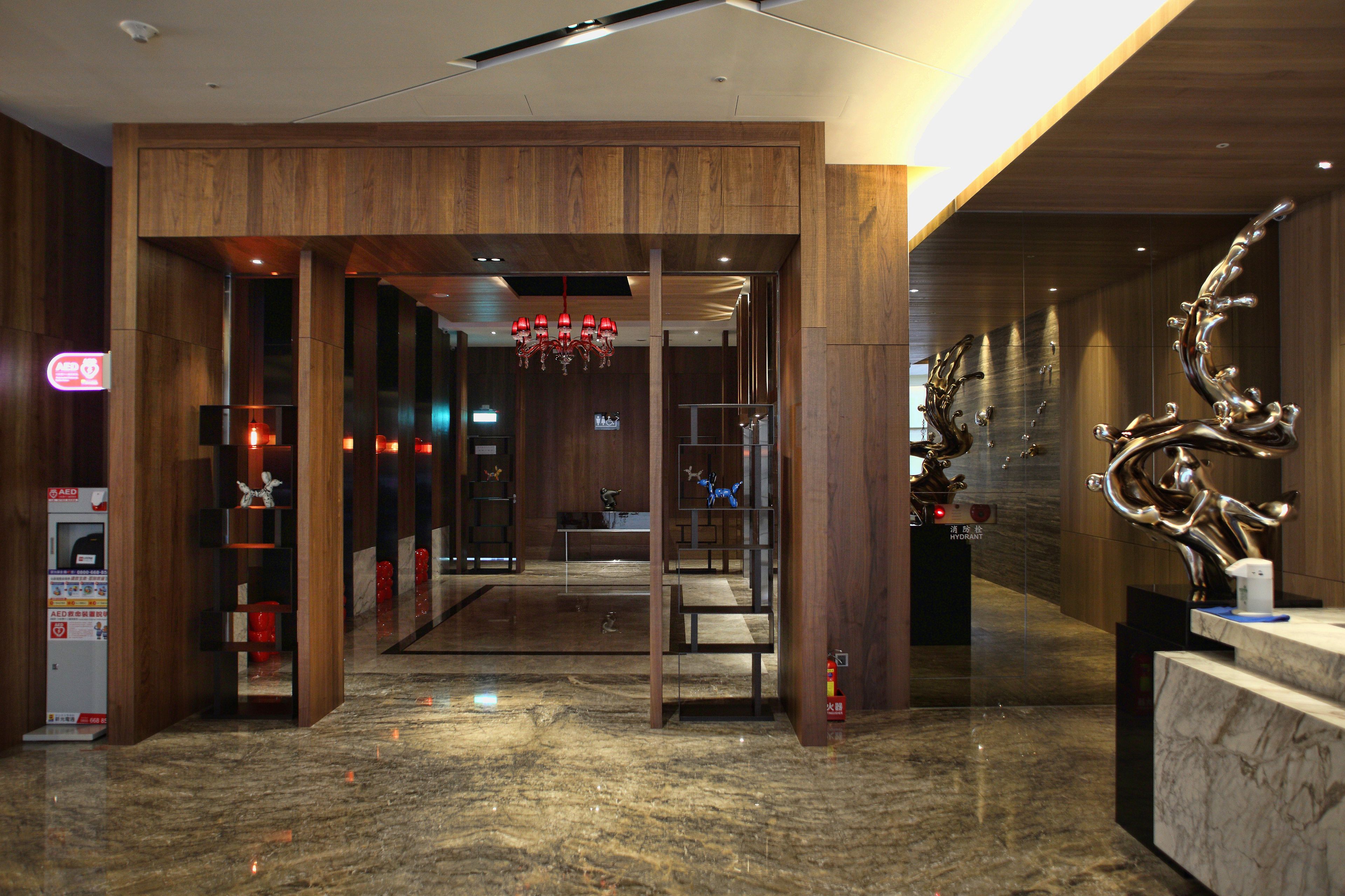A modern lobby with wooden paneling, a reception desk, and a chandelier.