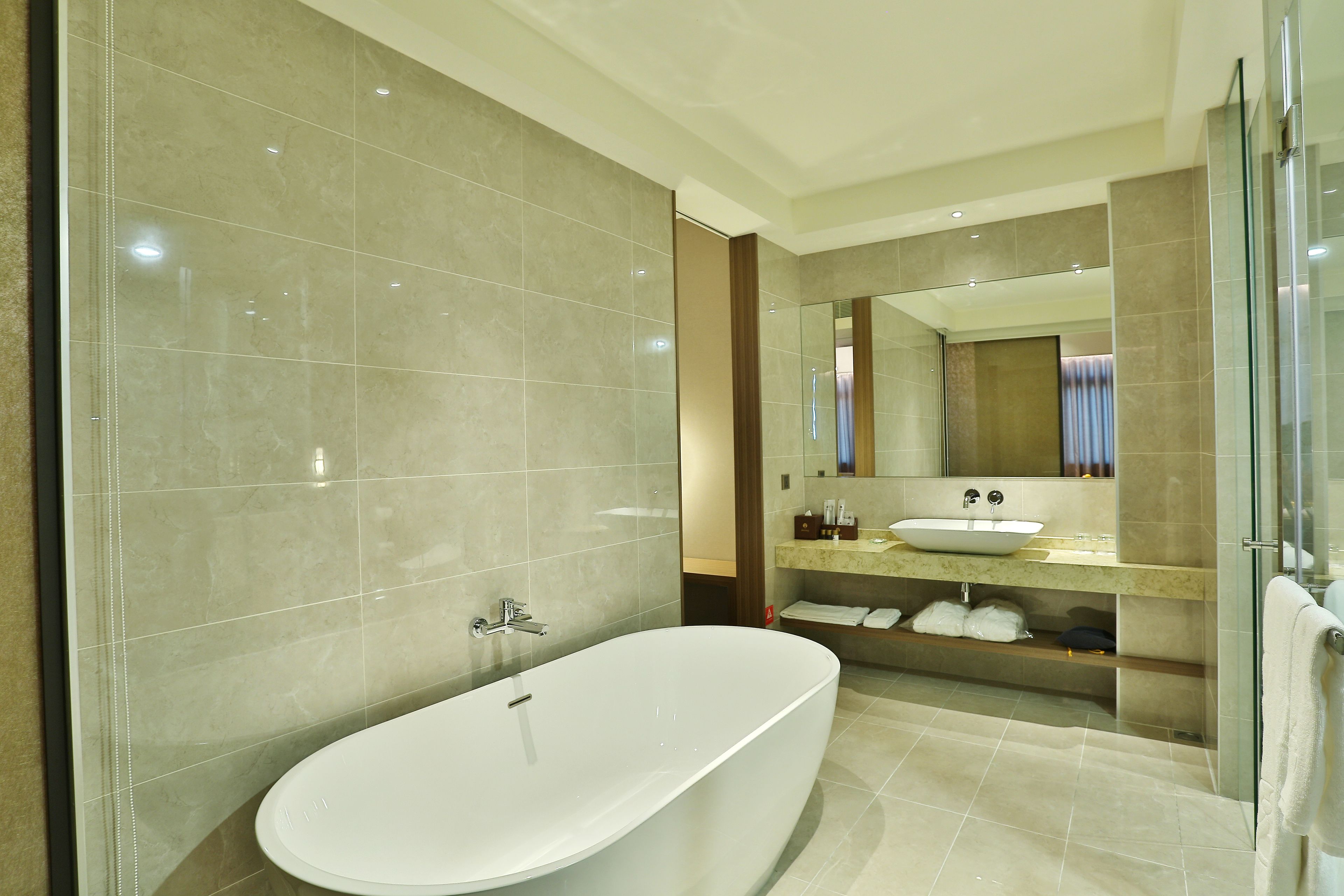 A modern bathroom with a freestanding bathtub, a glass-enclosed shower, and a vanity with a sink and mirror.