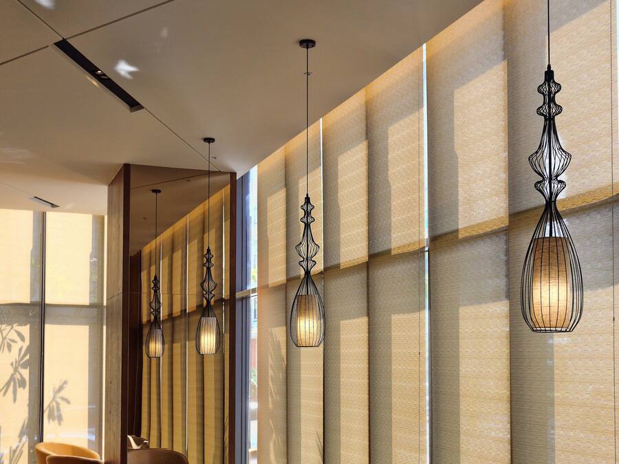 A modern interior with leather chairs and tables, large windows, and hanging pendant lights.