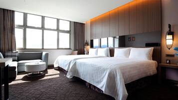 Habitación de hotel con dos camas, un sofá, una mesita de centro y un televisor.