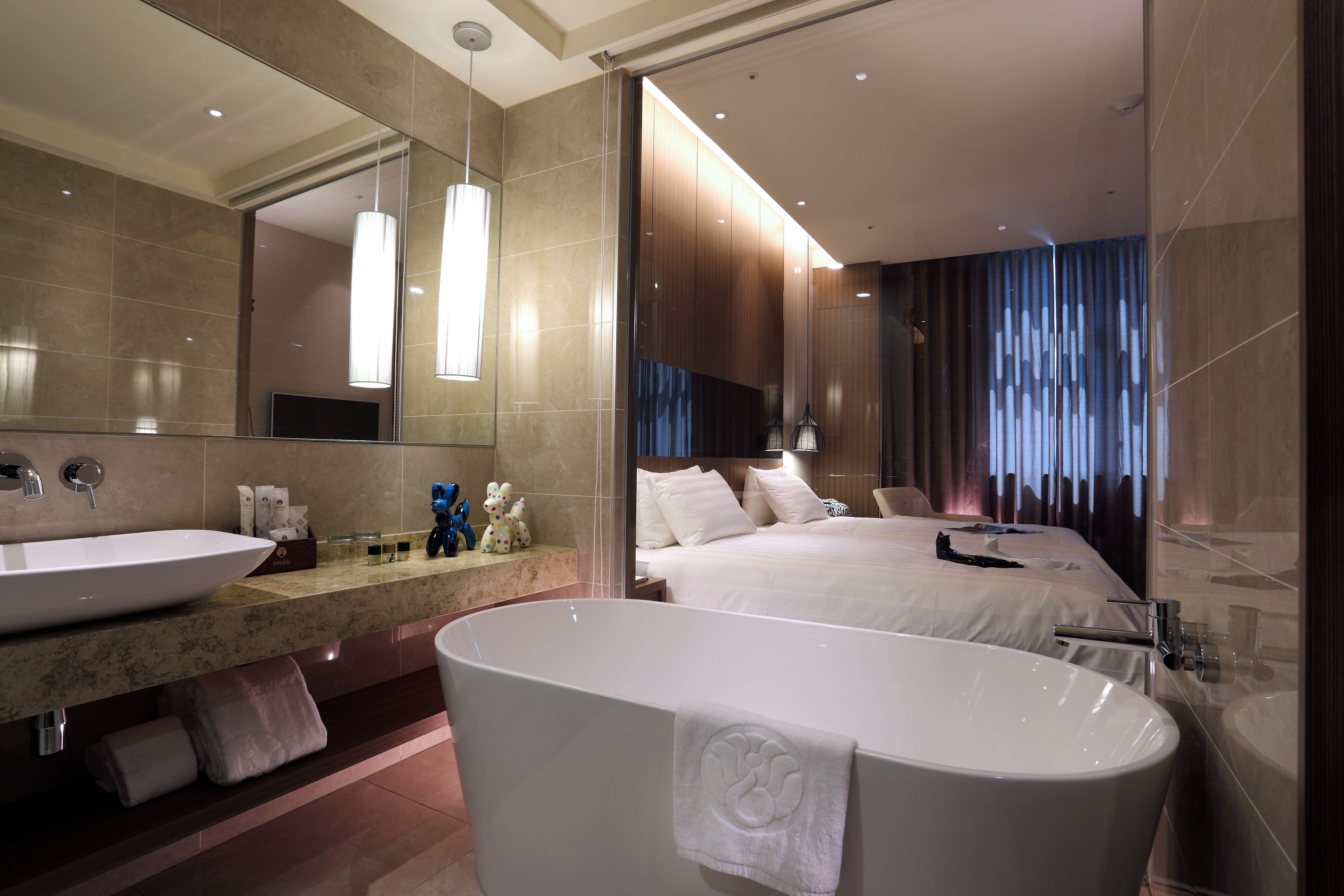 A modern hotel bathroom with a large bathtub, two sinks, and a large mirror.