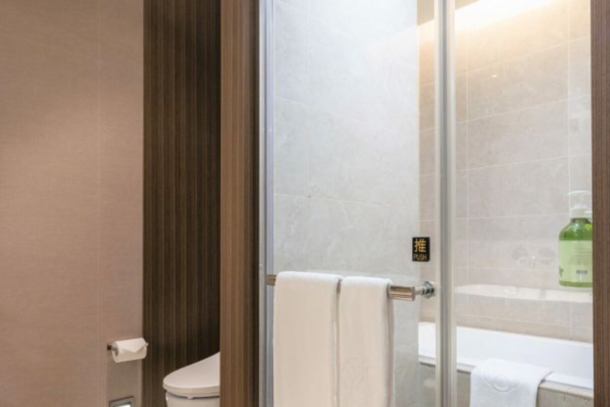A bathroom with a glass shower enclosure, a toilet, and a bathtub.