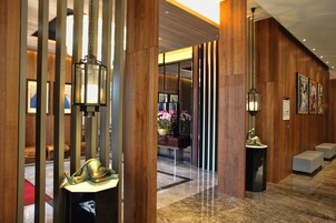 Un vestíbulo con paneles de madera, un mostrador de recepción, una estatua y una zona de estar.