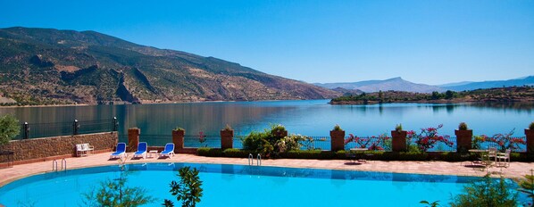 Una piscina al aire libre, sillones reclinables de piscina