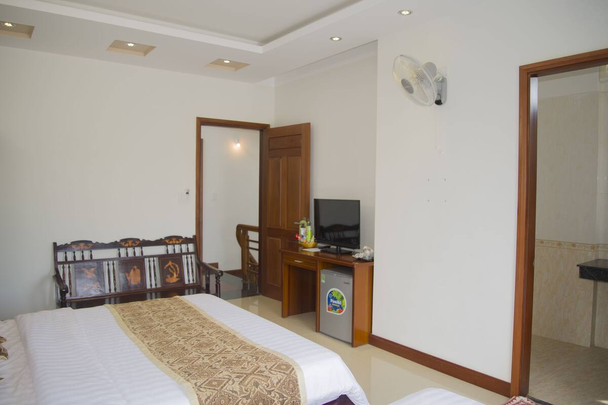Ein Hotelzimmer mit einem Bett, einem Schreibtisch mit Fernseher, einem kleinen Kühlschrank und einem Spiegel an der Wand.