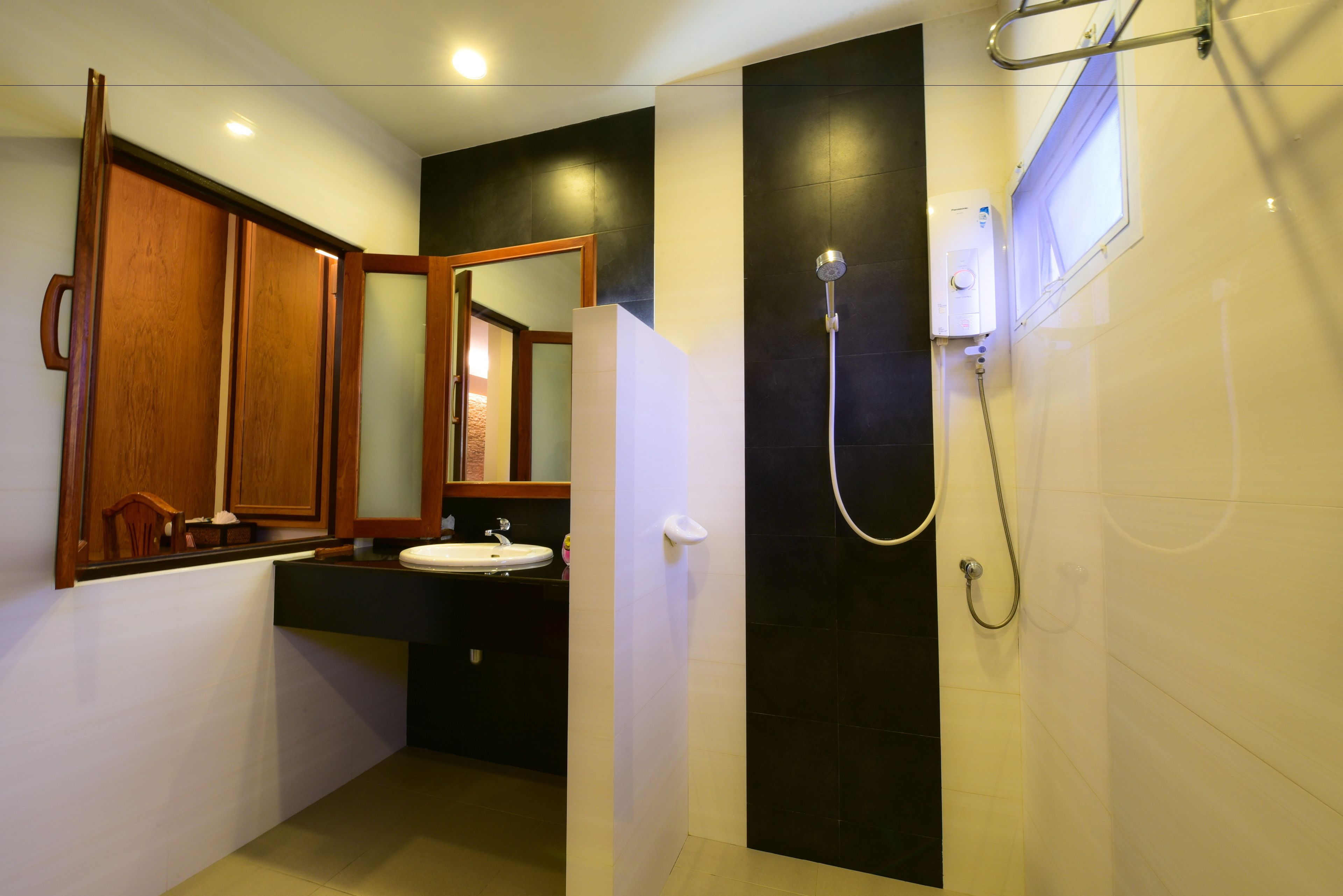 A bathroom with a wooden cabinet, a sink, a mirror, and a shower area.