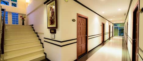 A hotel hallway with a staircase, a door, and a framed picture on the wall.