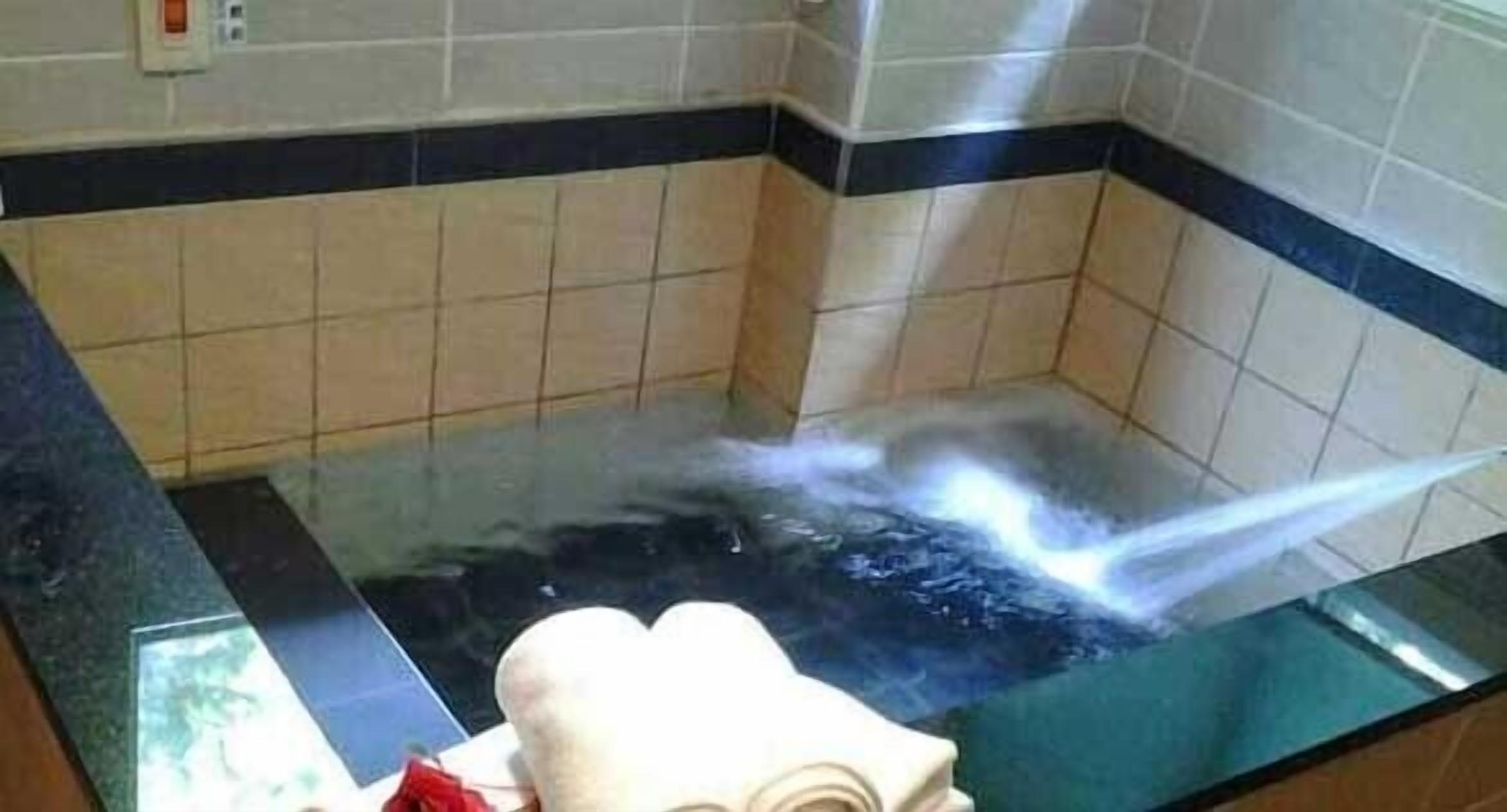 A hot tub with a clear view of the water jets, a towel, and a tiled wall.