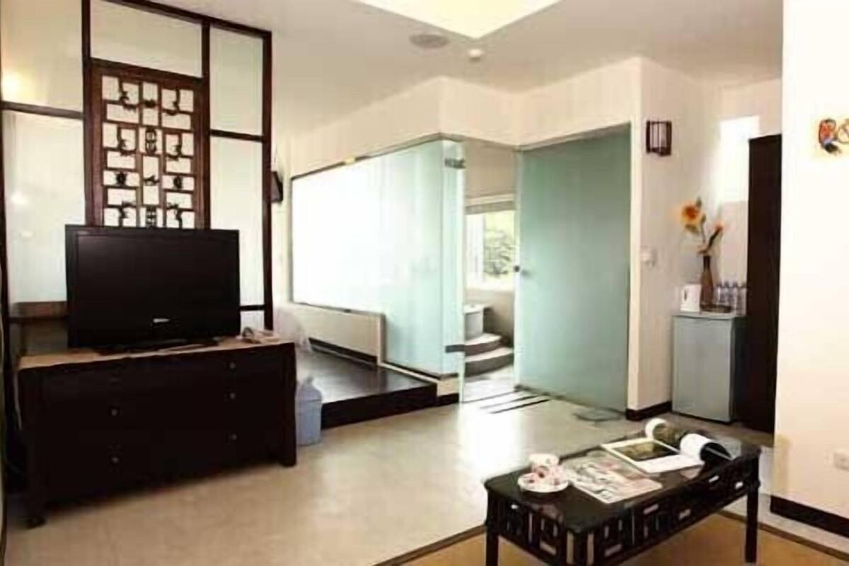 Una sala de estar con televisor, mesa de centro y sofá. Se ve una escalera que conduce a otra habitación.