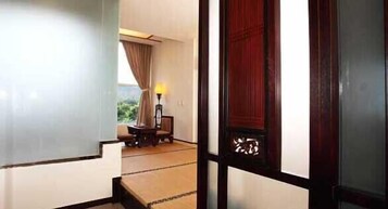 Una habitación japonesa tradicional con suelo de tatami, una mesa baja con una silla y una lámpara.