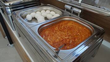 A buffet with a large serving of pasta and a tray of eggs.