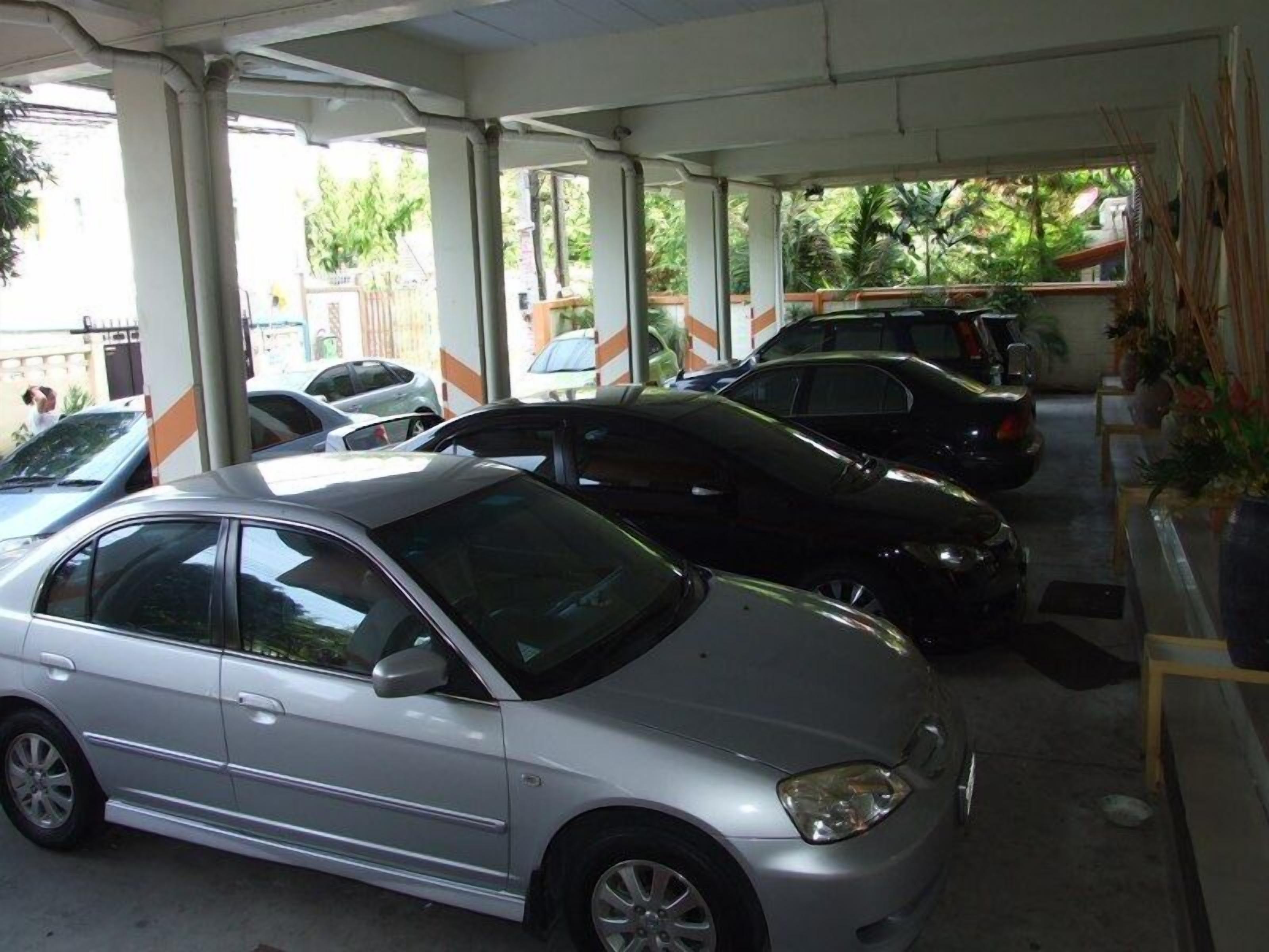 A parking area with multiple cars, including a silver sedan and a black car.