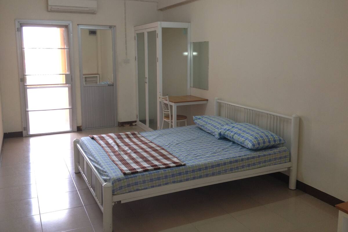 A bedroom with a bed, a desk, and a wardrobe.