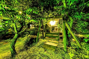 Escape to a serene oasis surrounded by lush greenery and a shaded pergola.