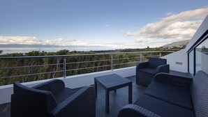 Un balcon doté de meubles en osier et offrant une vue sur la mer.