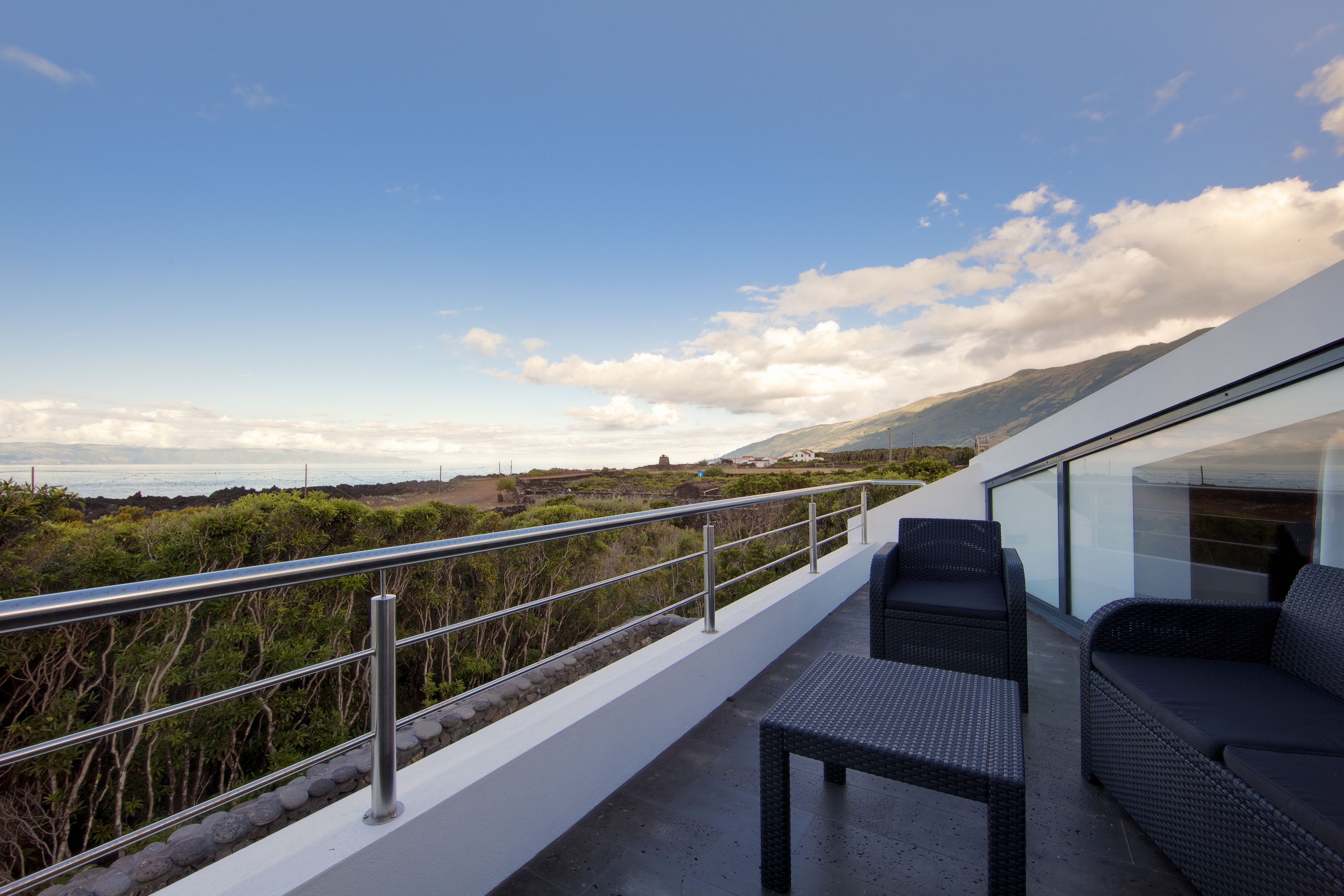 Un balcón con vista al mar y a las montañas, amueblado con un sofá y una mesa.