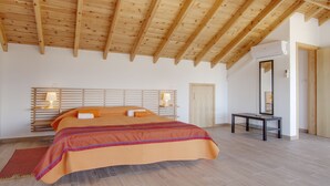 Une chambre spacieuse avec un plafond en bois, un grand lit, des lampes de chevet et une petite table.