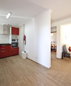 Una cocina moderna con armarios rojos, un microondas y un cubo de basura.