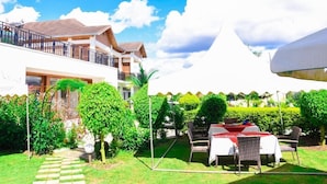 A hotel courtyard with a dining area, a covered seating area, and a building with a balcony. - Quiet Haven Hotel (Kigali)