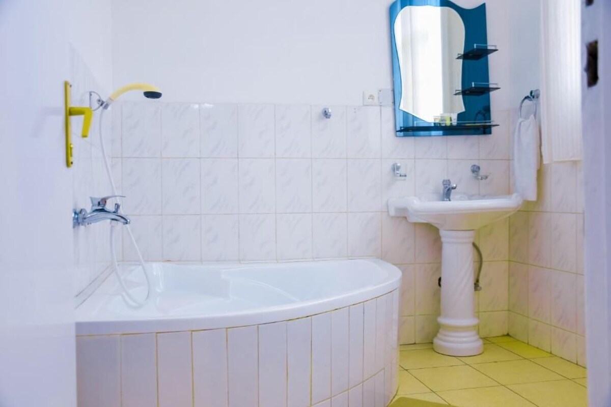 Un baño con una bañera blanca, un lavabo pedestal y un espejo sobre el lavabo.