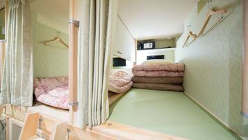 Habitación pequeña con literas, un escritorio y televisor.