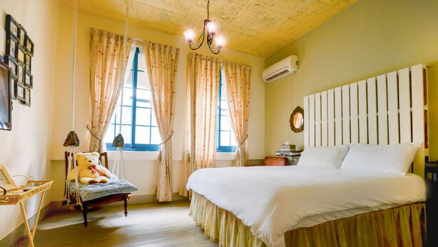 Quarto com cama, cadeira, janela e lustre.