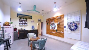 Um quarto bem iluminado com área de jantar, cozinha e uma parede decorada com um relógio e uma coroa de enfeites.