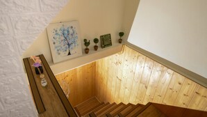 Uma escada de madeira com uma parede branca e um quadro emoldurado acima.