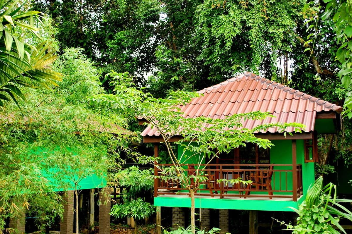 Une maison traditionnelle en bois, avec un toit recouvert de tuiles, entourée d’un feuillage verdoyant et luxuriant.