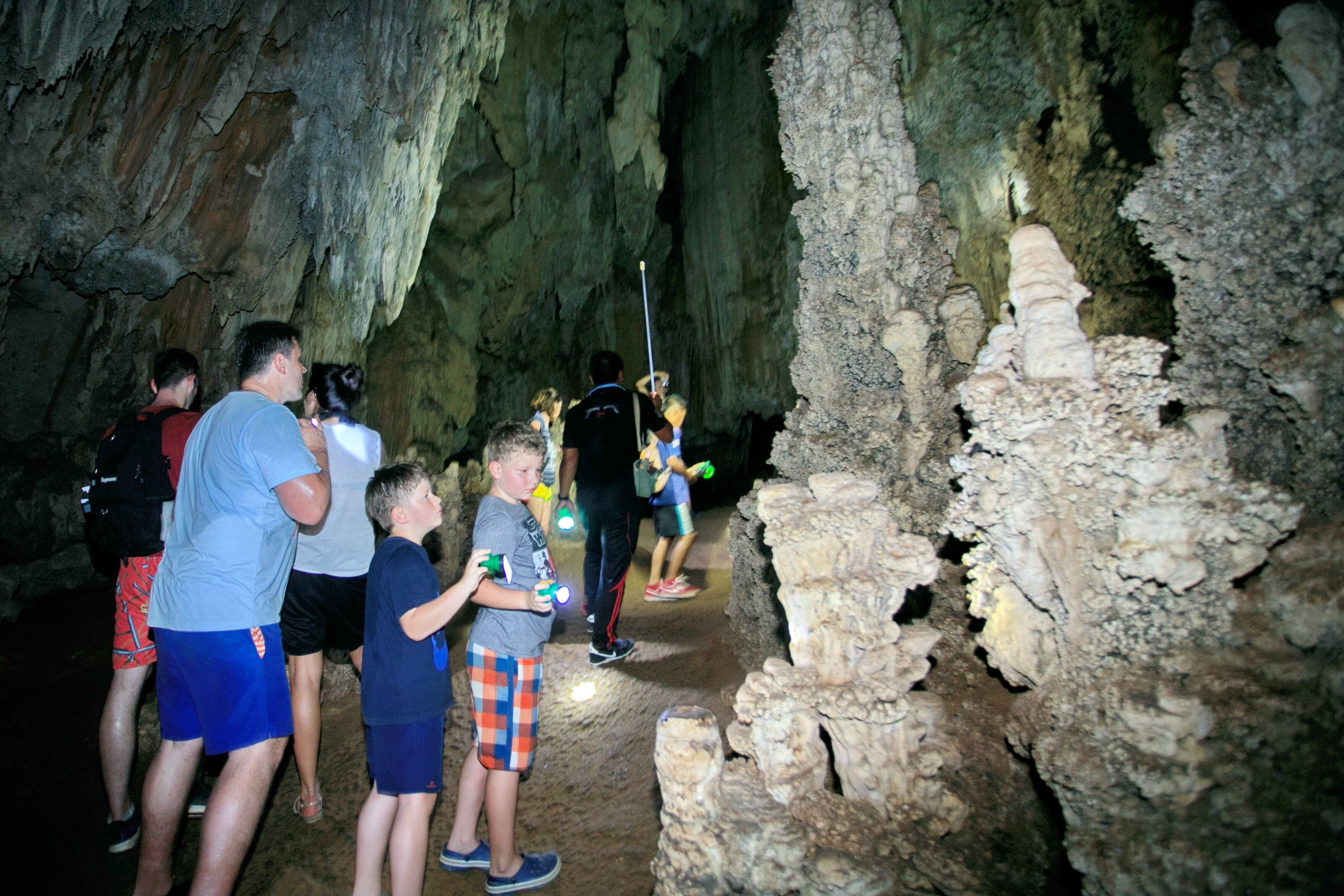 A group of people exploring a cave with stalactites and stalagmites.