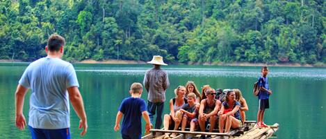 Un grupo de personas en una balsa de bambú en un lago rodeado de un bosque frondoso.