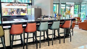 A modern bar area with a long counter and multiple stools.
