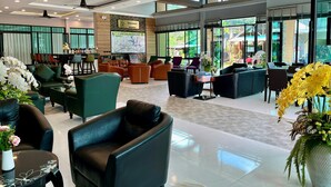 A spacious lobby with leather seating, a reception desk, and large windows offering views of the outdoors.