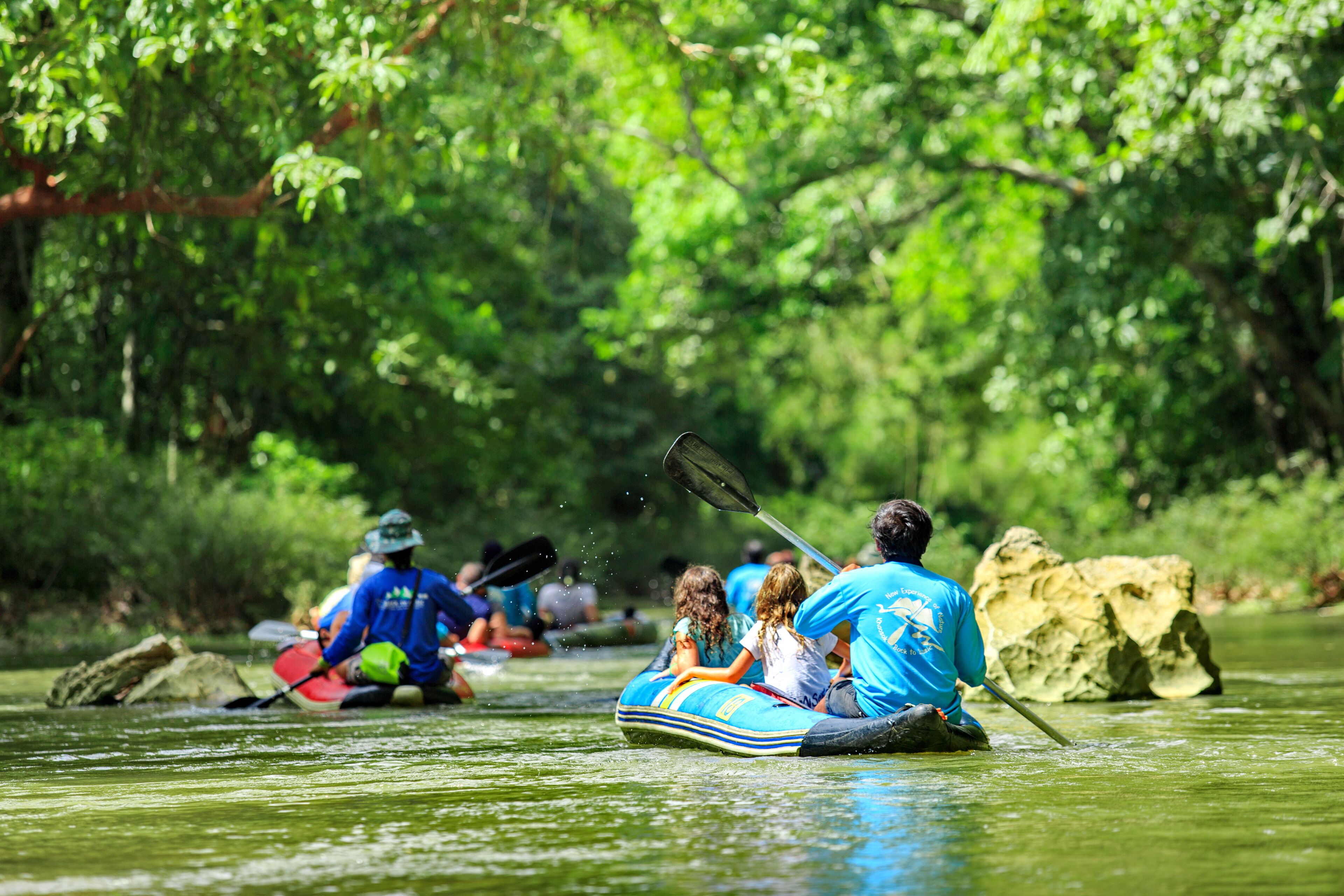 People in a raft on a river surrounded by greenery.