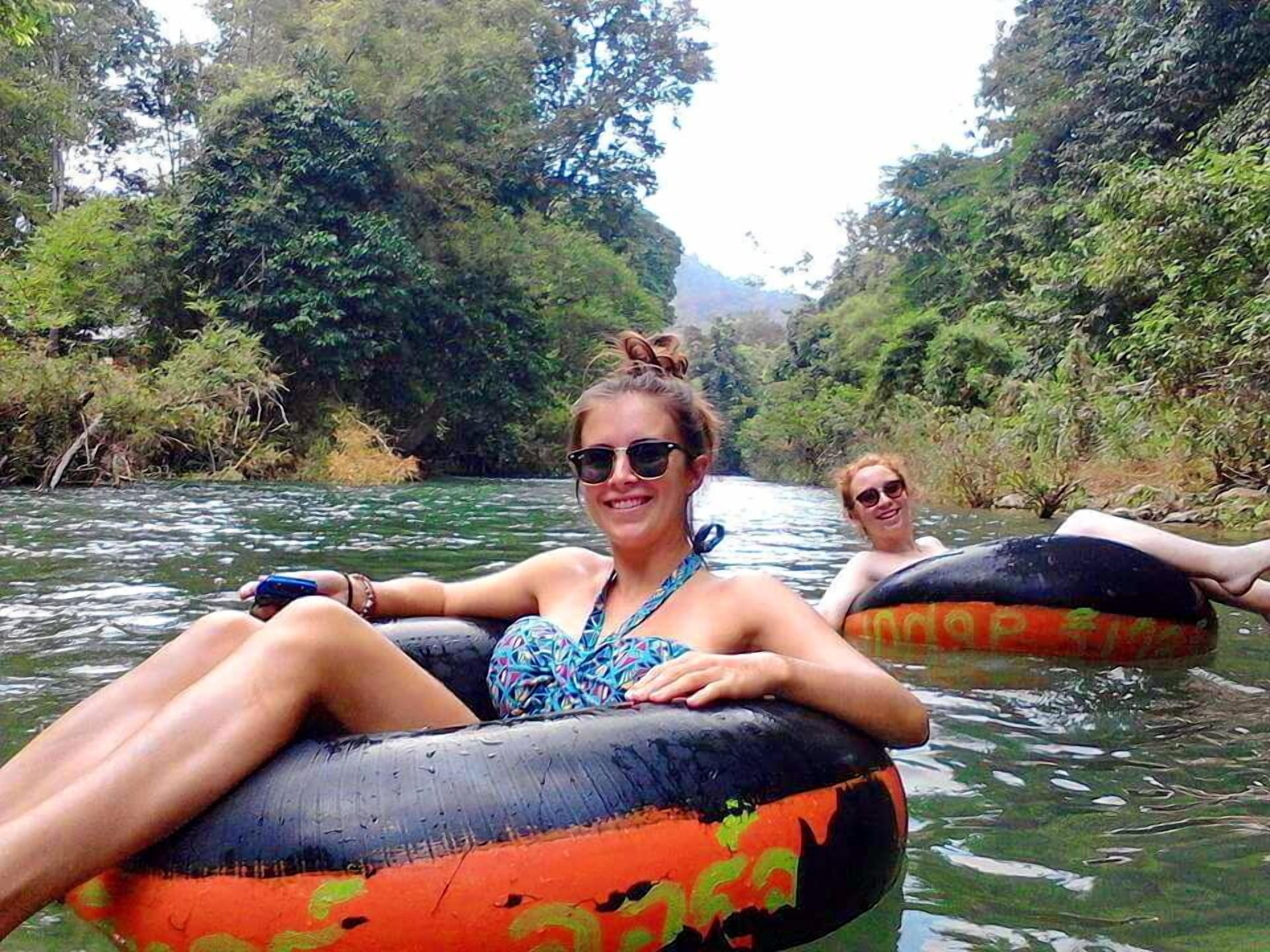 Two people floating on a river in an inflatable tube.