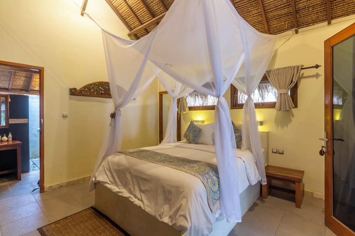 Een slaapkamer met een hemelbed, een nachtkastje en een bankje.