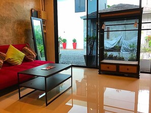 Un salon moderne avec un canapé rouge, une table basse en verre et une vue sur la rue.