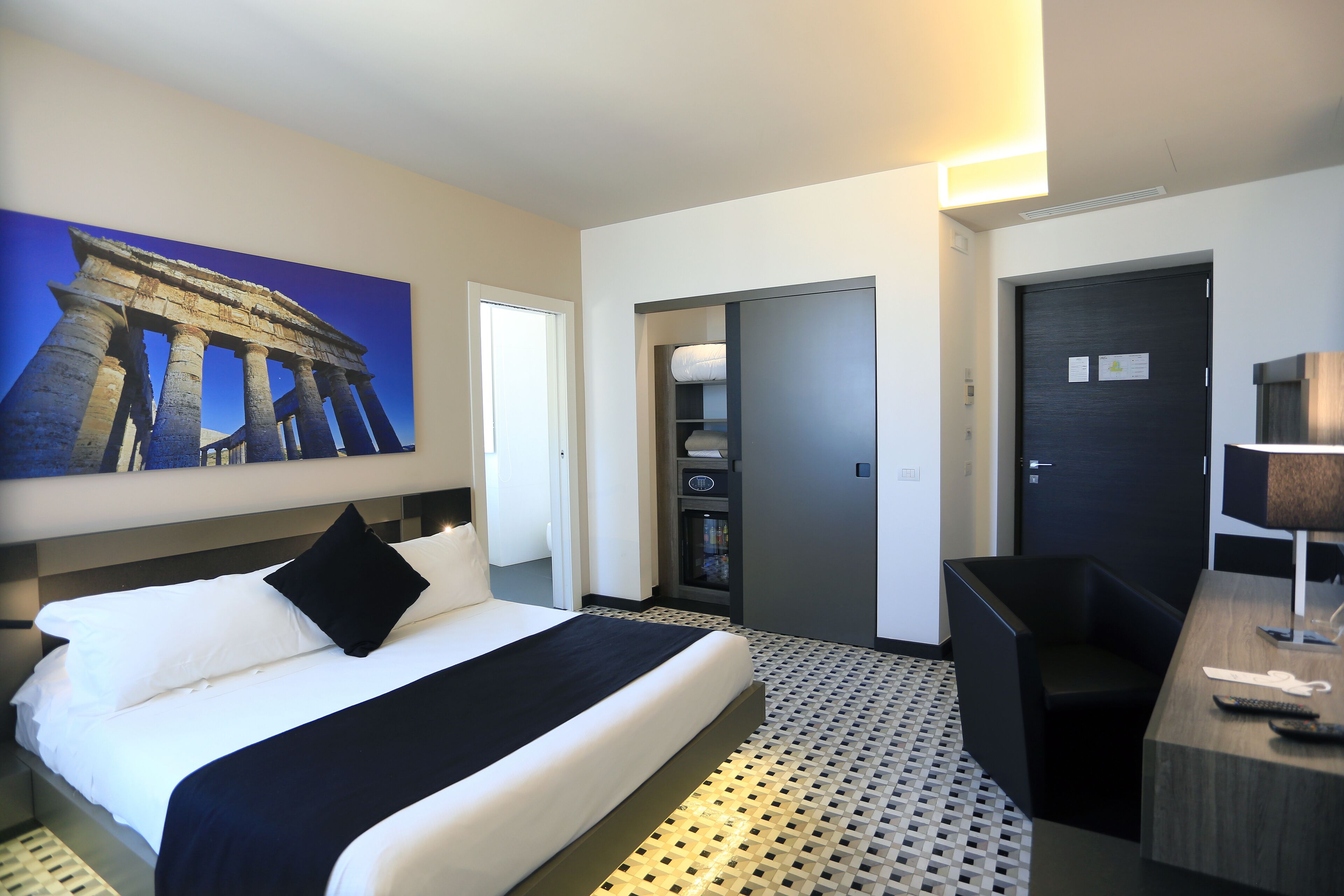 Een hotelkamer met een bed, een bureau, een kledingkast en een badkamer.