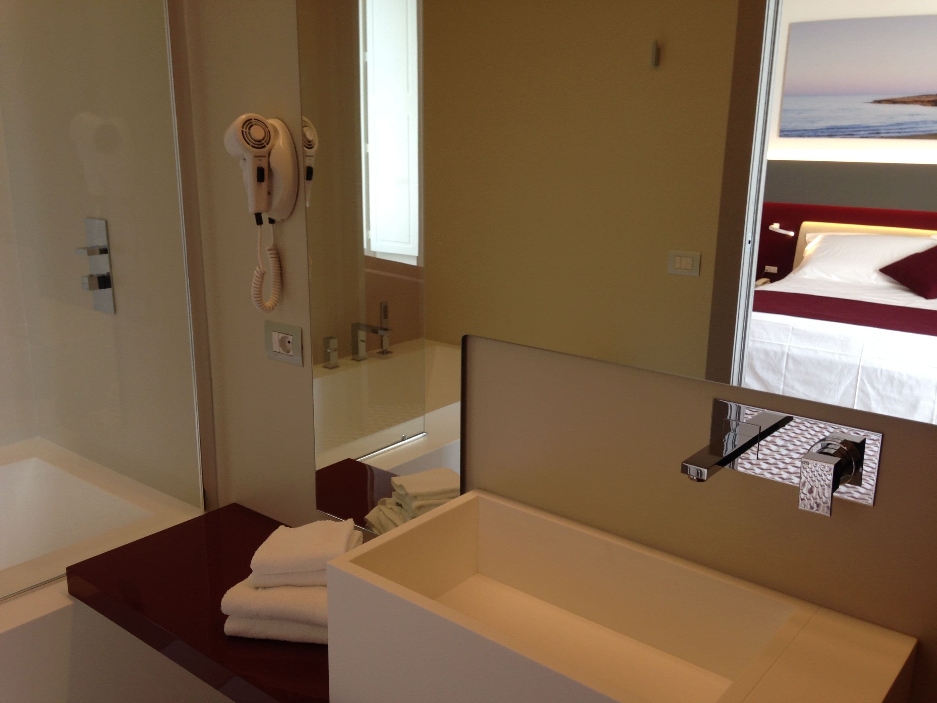 A bathroom with a white sink, a mirror, a hairdryer, and a towel rack.