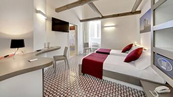 Ein modernes Hotelzimmer mit Bett, Nachttisch, Stuhl und Schreibtisch mit Lampe.