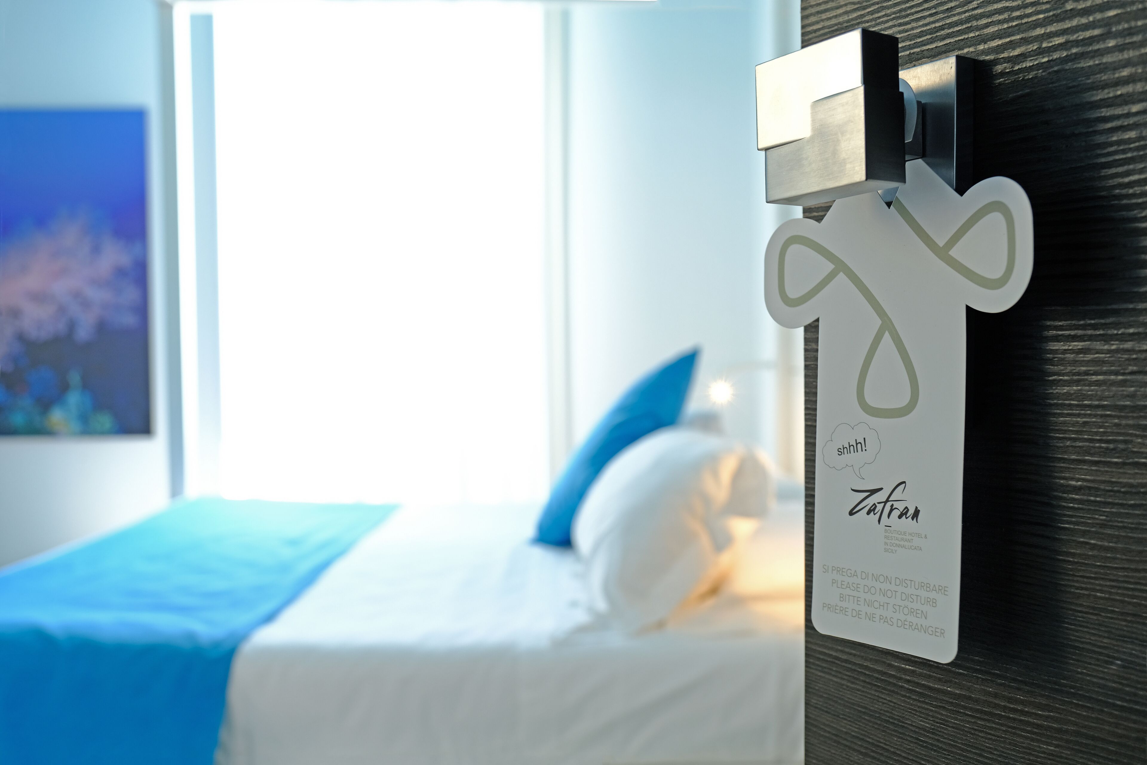 A hotel room with a bed, a blue pillow, and a sign on the wall.