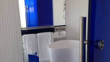 A modern bathroom with a white sink, a large bathtub, and a mirror above the sink.