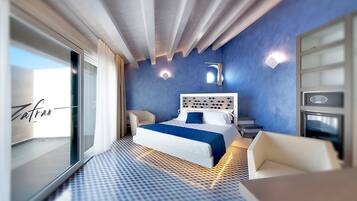 Habitación de hotel moderna con una cama grande, una zona de estar y vistas a través de un ventanal.