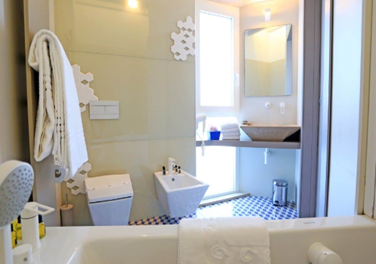 A bathroom with a bathtub, a sink, and a toilet. There is a towel rack and a mirror on the wall.