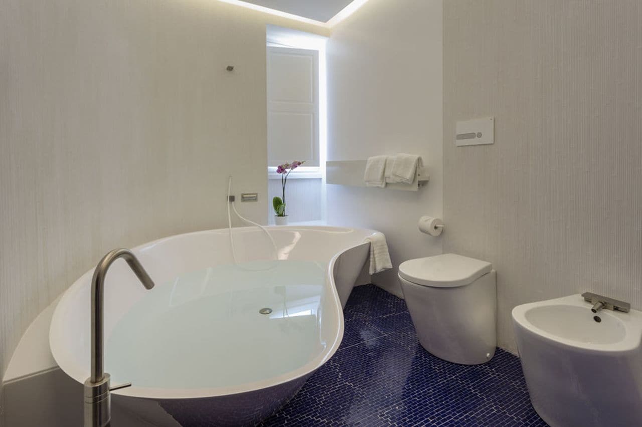 Une salle de bain moderne avec une baignoire sur pieds, des toilettes et un lavabo sur colonne.