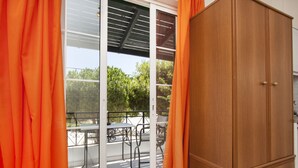 A room with a wooden wardrobe, a sliding glass door leading to an outdoor patio with a table and chairs. - Paul's Studio (Santorini)