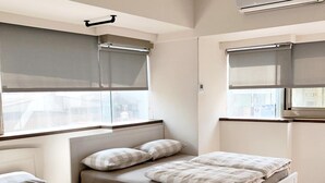 A bedroom with two beds, a window with a blind, an air conditioning unit, and a radiator. - Ahiruyah Guest House in Kaohsiung - Hostel (Kaohsiung)