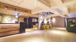 A modern interior with a wooden reception desk, a bar area, and a green couch. - Ahiruyah Guest House in Kaohsiung - Hostel (Kaohsiung)