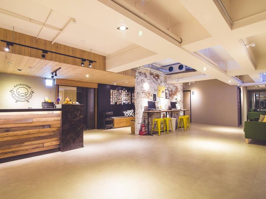 Um interior moderno com uma receção em madeira, área de bar e um sofá verde.