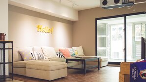 A modern living room with a sectional sofa, a coffee table, and a 'Hello!' sign on the wall. - Ahiruyah Guest House in Kaohsiung - Hostel (Kaohsiung)